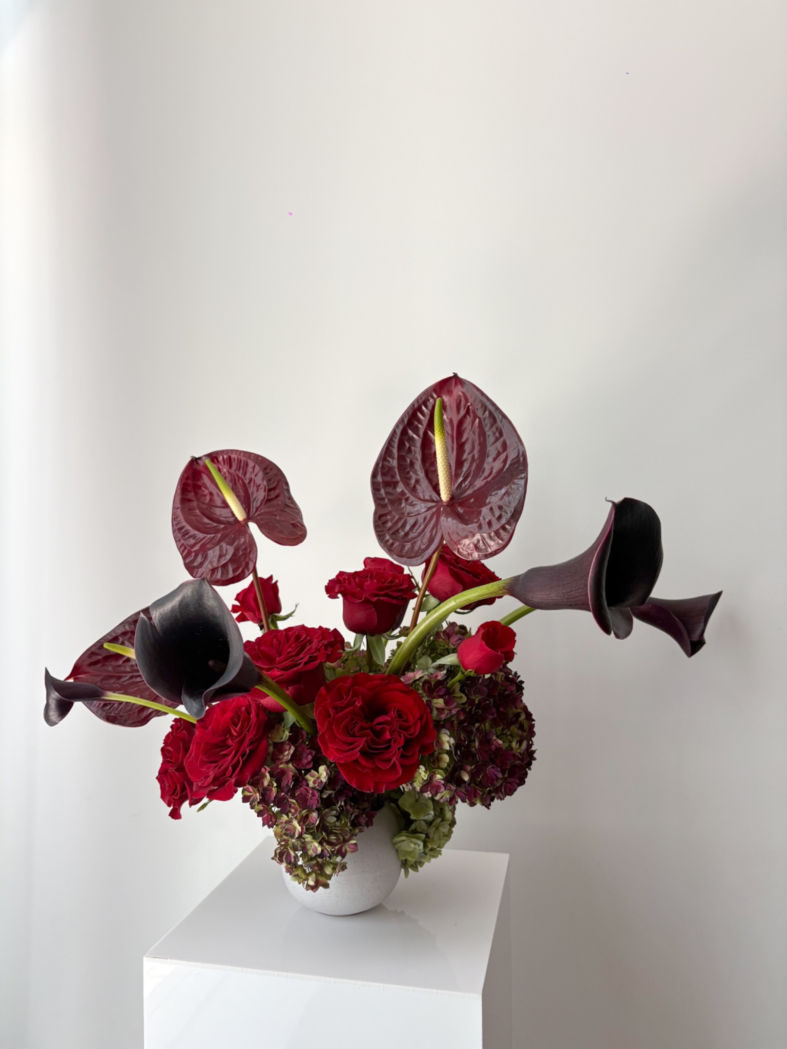 Red anthurium, rose, hydrangea, and black calla lily sculptural floral arrangement by Wilted NYC