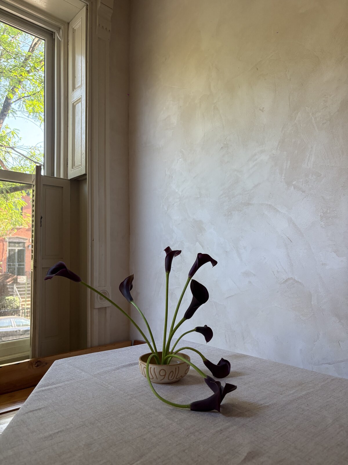 Sculptural dark calla lily arrangement in a ceramic vessel by Wilted NYC