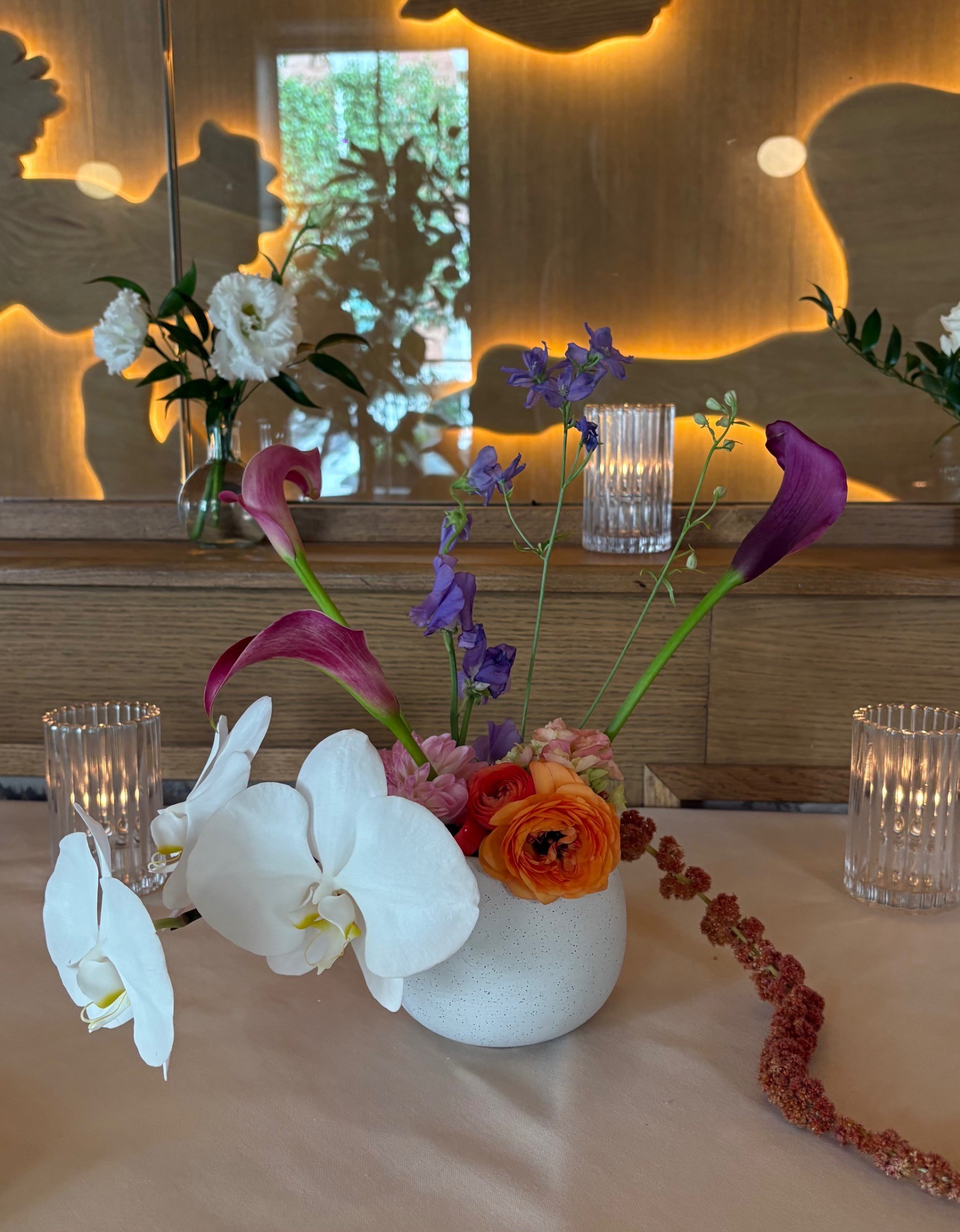 Restaurant table floral arrangement with orchids, calla lilies, ranunculus, and amaranthus by Wilted NYC